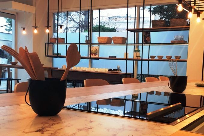 Captivating kitchen scene with a wooden table hosting a large hot plate and a bowl filled with wooden spoons, promising culinary exploration and delicious creations.